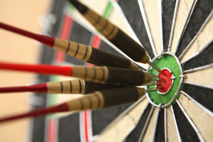Five darts hitting bullseye on dartboard