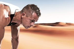 Extreme athlete runner man in starting position outdoor in desert